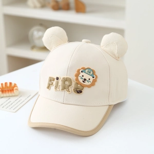 Détail du patch lion et oreilles 3D sur une casquette en coton beige pour garçons