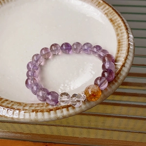 Macro shot of purple amethyst beads and yellow citrine stone in a ceramic dish