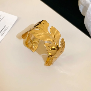 Detailed macro shot of the golden monstera leaf texture on the open metal cuff bracelet