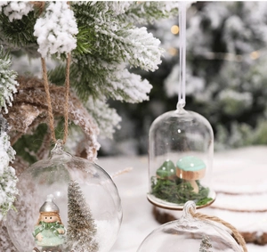 Close-up of Nordic glass Christmas baubles with miniature scenes on snowy branches