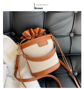 Detail of canvas bucket bag with brown leather trim, drawstring closure and metal hardware