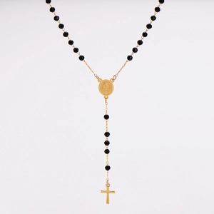 Macro shot of gold St. Benedict medal and cross pendant on black faceted bead chain