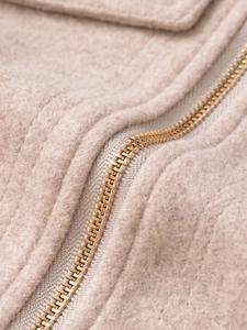 Macro view of beige soft fleece fabric and premium gold metal zipper detailing