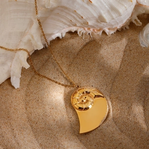 Detailed close-up of golden conch pendant necklace on beach sand with sea shells