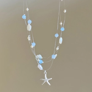 Détail d'un collier multicouche avec étoiles de mer, coquillages, perles et billes bleues