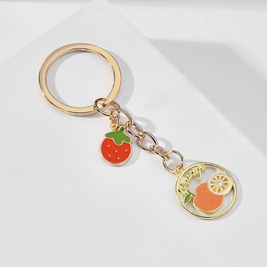 Detail view of gold alloy keychain with red strawberry and orange enamel fruit charms