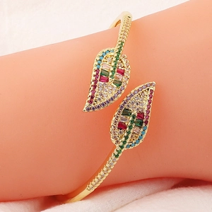Detail of leaf-shaped gold plated bracelet with colorful zircon stones on model wrist