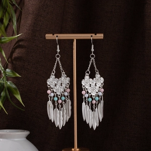 Detail of silver bohemian earrings with turquoise beads and metallic feather charms