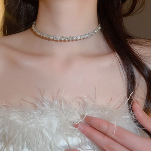 Close-up of a silver-toned diamond choker necklace worn by a model with feather accents