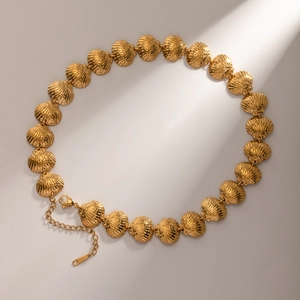 Detailed view of a gold shell link necklace with adjustable lobster clasp on light background