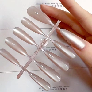 Detail van parelroze cat-eye plaknagels in lange stiletto-vorm op een houder