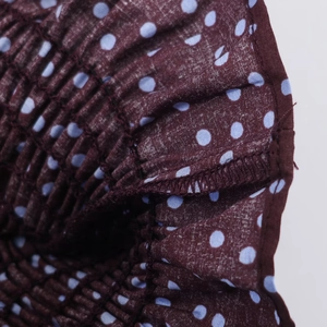 Detail of dark purple polka dot blouse showing smocking elastic and seam stitching