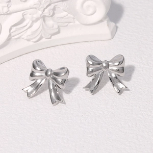 Close-up of elegant silver bow stud earrings in polished stainless steel for women