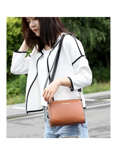 Detail of brown leather crossbody bag with gold hardware and black slim strap on model