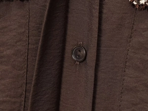 Detailed macro view of smooth dark coffee woven fabric and premium round button detail