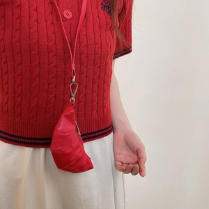 Détail d'un mini sac croissant rouge avec fermoir argenté porté sur un polo rouge en maille