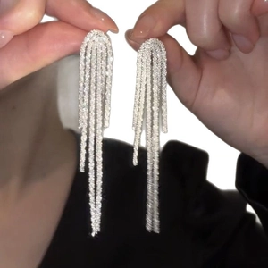 Elegant silver tassel earrings with sparkling rhinestones held for a shimmering visual effect