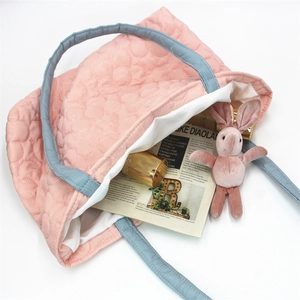 Close-up of pink floral quilted tote bag with blue handles and spacious white interior