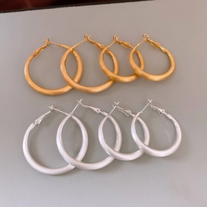 Dettaglio di orecchini a cerchio opachi spazzolati oro e argento con chiusura a leva
