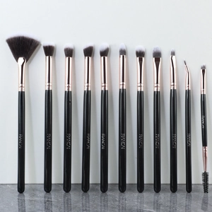 Macro view of 12 black and rose gold makeup brushes with soft gradient bristles