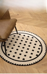 Close-up of thick cream round carpet with black polka dots on herringbone wood floor