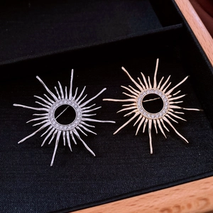 Detail shot of gold and silver sunburst brooches with pavé zircon in a wood frame tray