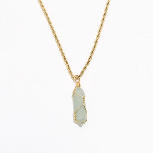 Detailed macro view of light green hexagonal crystal pendant with gold wire wrap on chain