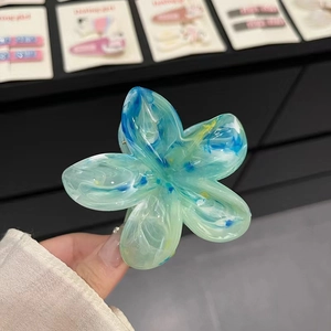 Détail d'une pince à cheveux fleur au motif marbré bleu avec finition translucide