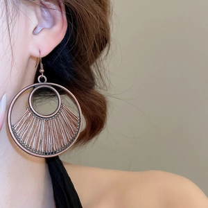Close-up of vintage bronze geometric hollow earrings with woven texture on a model