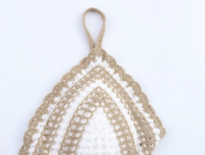 Detailed close-up of handmade crochet halter top with white and khaki knit patterns