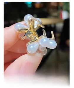 Gros plan d'une mini pince à cheveux dorée avec d'élégantes perles blanches