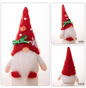 Detail view of red knitted Christmas gnome featuring white beard and snowflake ribbon bow