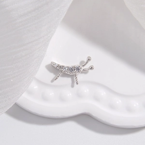 Détail macro de bijoux insectes en argent avec zircons clairs sur plateau blanc