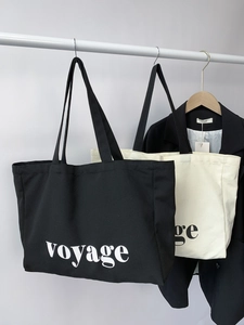 Detail of hanging black and cream canvas tote bags with voyage letter print design
