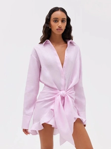 Detail of light pink linen shirt dress showing waist bow tie and ruffled hemline