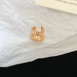 Macro detail of double-layered gold ear cuff featuring hammered and textured surfaces