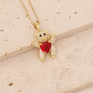 Detailed close-up of golden bear pendant with red heart stone and zircon stones
