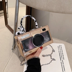 Fashionable gold mirror camera-shaped handbag with silk scarf and decorative feathers