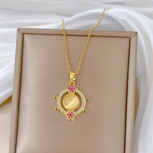 Detailed close-up of a gold necklace pendant with yellow stone and pink stars