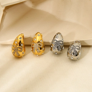Macro view of gold and silver teardrop earrings with rhinestone bow details