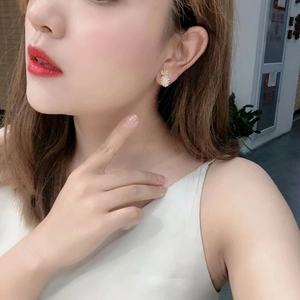Elegant gold pineapple pearl earrings worn by a model in a casual lifestyle setting