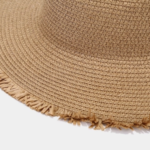 Detailed macro view of woven straw sun hat with natural fibers and decorative frayed edges