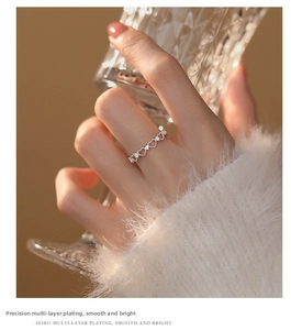 Detail of hollow heart-shaped silver ring with zircon inlays on model holding a glass