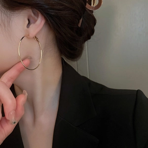 Gros plan d'élégantes créoles dorées portées par un mannequin pour un look chic et raffiné