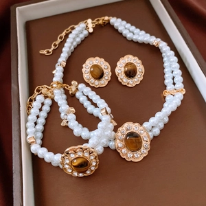 Dettaglio del set di gioielli vintage con perle e pendenti ovali dorati con pietre marroni