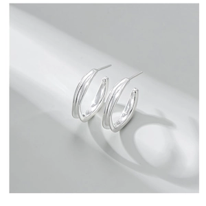Close-up of polished S925 sterling silver C-shaped hoop earrings with minimalist metallic luster