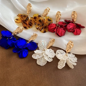 Flat lay of bohemian acrylic petal tassel earrings in amber, red, blue, and pearl white