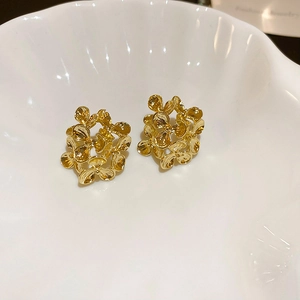 Macro di orecchini a forma di fiore in metallo dorato su un vassoio a conchiglia