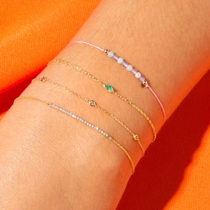 Macro shot of 4-piece layered bracelets with green zircon and gold chain on wrist