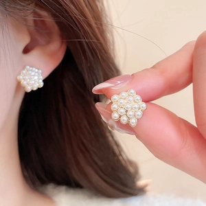Detail of floral pearl cluster earrings in gold setting worn by model on ear